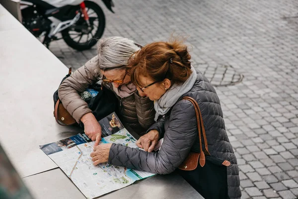 Two mature women looking at a map. — Stock Photo, Image