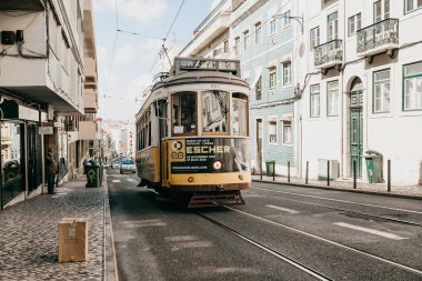 Geleneksel sarı eski moda veya retro tarzı tramvayla şehir Lizbon Portekiz sokak aşağı.