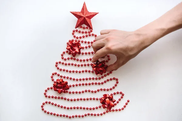 Una persona fa un albero di Natale o Capodanno creativo fatto di perline in stile minimalista e decora con una stella. . — Foto Stock