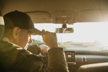 Sürücü veya turist arabadaki beyzbol şapkası ayarlar