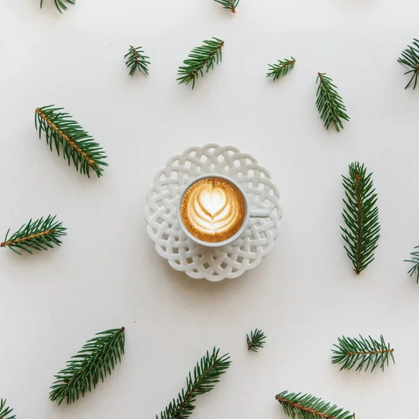 A cup of fresh fragrant cappuccino coffee next to the fir branches in the Christmas or New Years style. — Stock Photo, Image