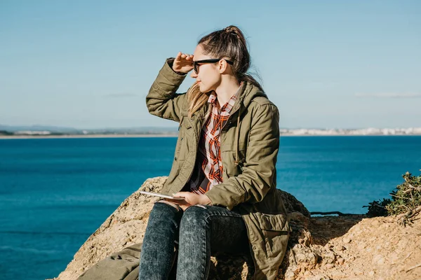 Una joven o turista usa una tableta y mira a la distancia . — Foto de Stock