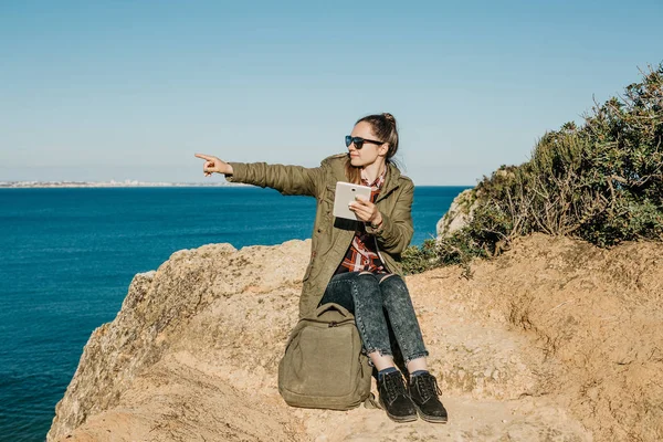 Mujer joven o turista utiliza una tableta y muestra una mano en la distancia — Foto de Stock