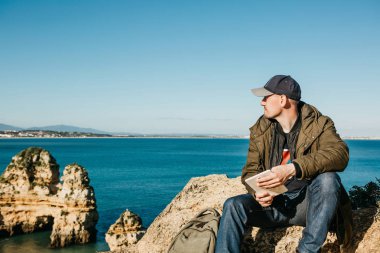 Genç bir adam bir tablet kullanır ve mesafe içine görünüyor.