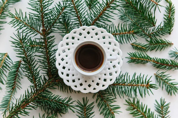 Une tasse d'expresso fraîchement aromatisé ou de thé noir à côté des branches d'épinette dans le style de Noël ou du Nouvel An . — Photo