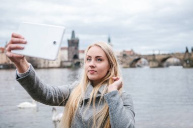 Bir güzel genç sarışın bir kadın veya selfie ya da kendini Çek Cumhuriyeti Prag fotoğraf çekme turist. Charles Bridge içinde belgili tanımlık geçmiş.