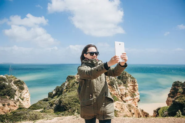 Una joven turista toma fotos en una tableta o filma un video para recordar o habla con alguien en línea . — Foto de Stock