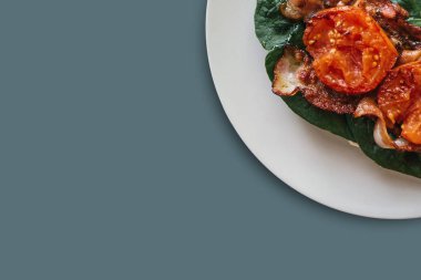 Yakın çekim. Pastırma, ıspanak ve gri arka plan üzerinde domates ile lezzetli ve besleyici yemek. Lezzetli yemekler. Metin için yakındaki yer