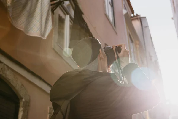 Um fotógrafo de rua ou um jovem tira fotos de casas autênticas em Lisboa, em Portugal. Um fotógrafo profissional ou turista tirar fotos para a memória — Fotografia de Stock