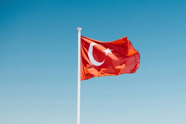 Una bandera turca en un asta de la bandera contra un cielo azul — Foto de Stock