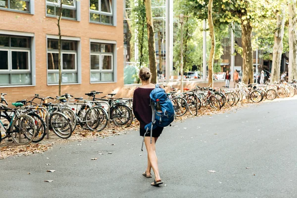 Студент дівчини або турист переходить дорогу і йде на стоянковий велосипед — стокове фото