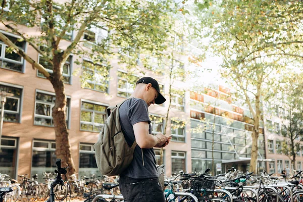 Un estudiante con una mochila o un turista en la calle Leipzig en Alemania usa un teléfono celular . — Foto de Stock