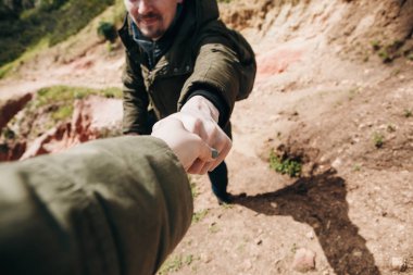 Bir uzun yürüyüşe çıkan kimse başka bir kişiye bir dağlık alanda yürüyüş sırasında bir el verir.