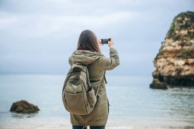 Kız turist Atlantik kıyısında bekleyen bir güzel manzara fotoğrafçılığı bir sırt çantası ile