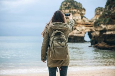 Kız turist Atlantik kıyısında bekleyen bir güzel manzara fotoğrafçılığı bir sırt çantası ile