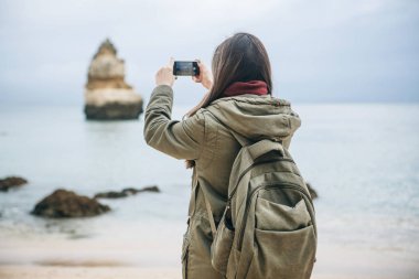Kız turist Atlantik kıyısında bekleyen bir güzel manzara fotoğrafçılığı bir sırt çantası ile
