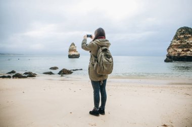 Kız turist Atlantik kıyısında bekleyen bir güzel manzara fotoğrafçılığı bir sırt çantası ile