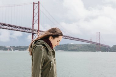 Güzel bir kız yalnız Lizbon Köprüsü yakınlarında ve kıyı yürür..