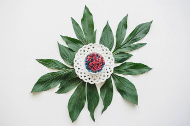 Çeşitli meyveler ile dolu bir kupa yeşil yapraklarda standları.