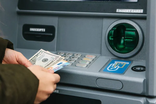 Una mujer joven toma dinero de un cajero automático . — Foto de Stock