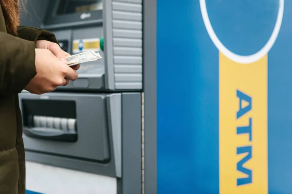 Una mujer joven toma dinero de un cajero automático . — Foto de Stock