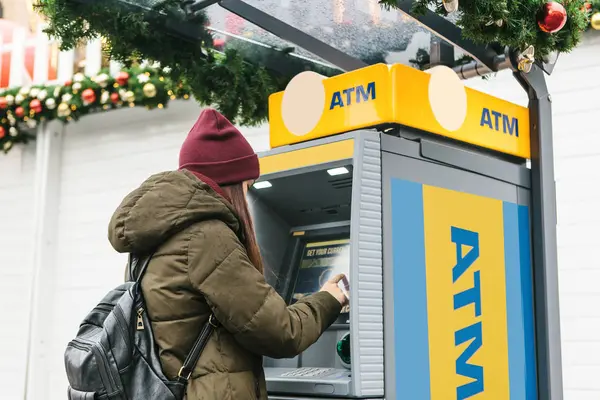 Una mujer joven toma dinero de un cajero automático . — Foto de Stock