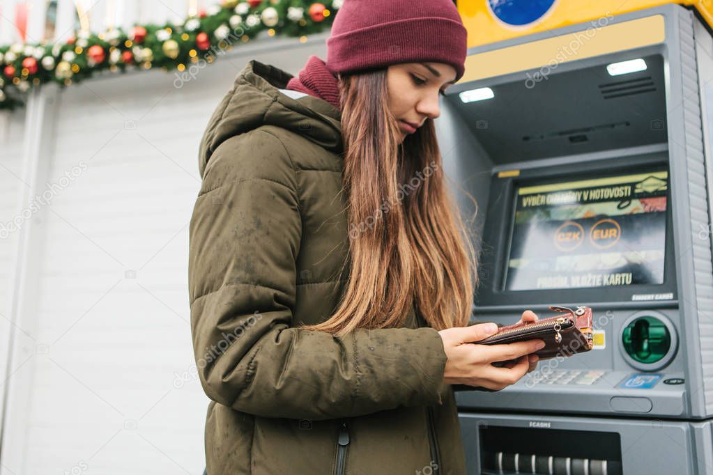 A young woman takes money from an ATM.