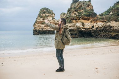 Kız turist Atlantik kıyısında bekleyen bir güzel manzara fotoğrafçılığı bir sırt çantası ile.