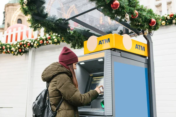 Una mujer joven toma dinero de un cajero automático . — Foto de Stock