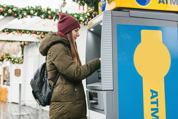 Een jonge vrouw neemt geld uit een Geldautomaat. — Stockfoto