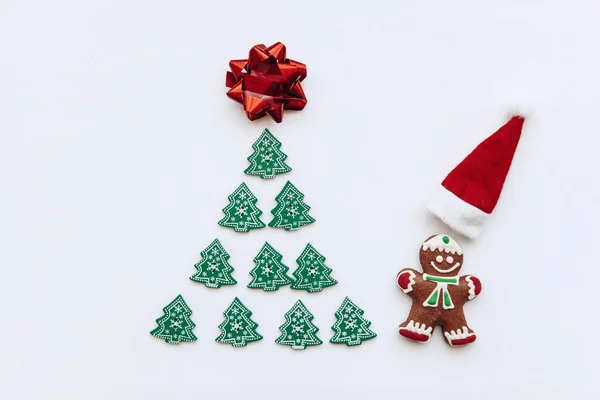 Рождественская елка из других небольших деревянных деревьев и рядом рыжий маленький человек и рядом с ним красная шляпа Санта-Клауса . — стоковое фото