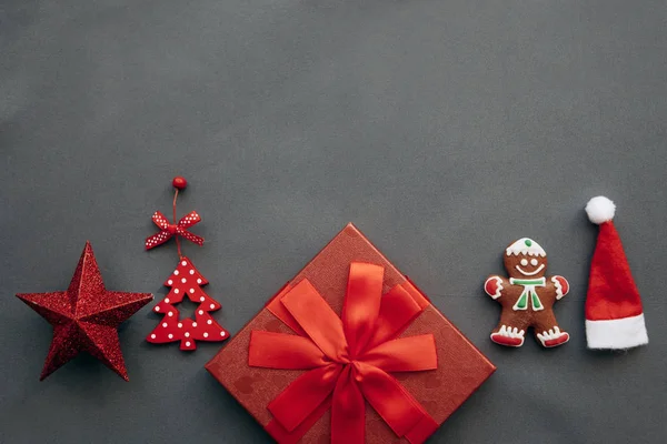 Праздничная красная коробка с луком и рядом с ней различные рождественские украшения, игрушки и еда . — стоковое фото