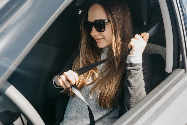 La chica está sujetando el cinturón de seguridad en el coche antes del viaje — Foto de Stock