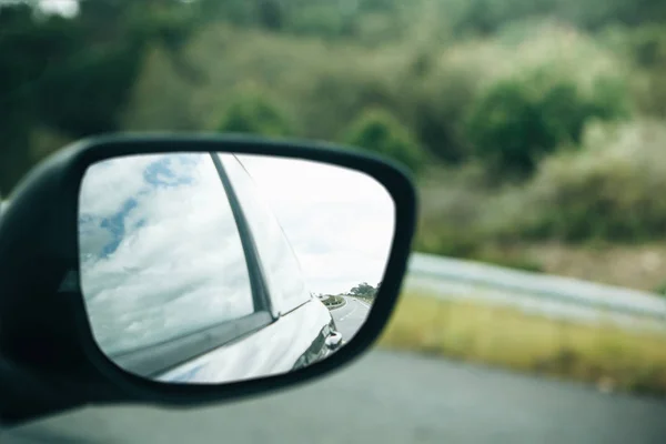 Um close-up de um espelho retrovisor do carro enquanto dirige em uma estrada de asfalto ou uma auto-estrada — Fotografia de Stock