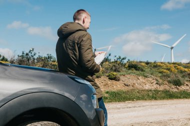 Bir turist adamın arabanın yanında daha fazla seyahat için bölgenin haritasına bakar