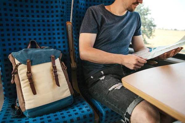 Турист сидит у окна в поезде или пригородном поезде и смотрит на карту — стоковое фото