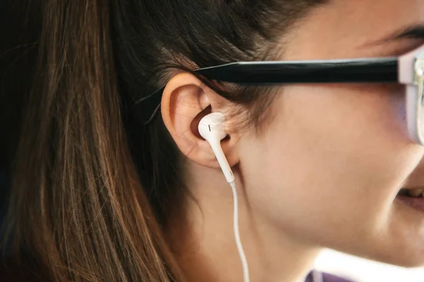 Close-up de uma menina com fones de ouvido ouvindo música ou um podcast — Fotografia de Stock