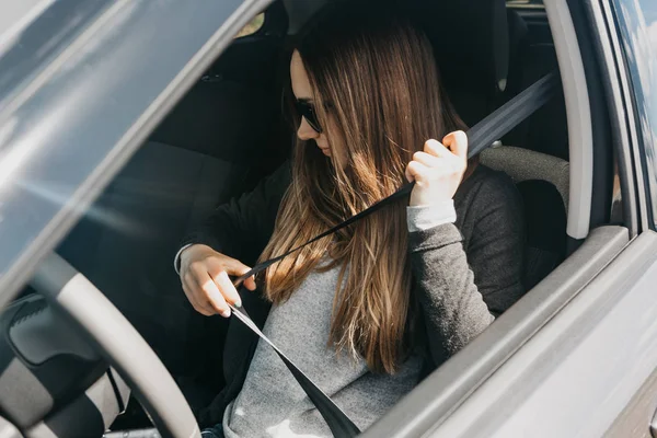La chica está sujetando el cinturón de seguridad en el coche antes del viaje — Foto de Stock