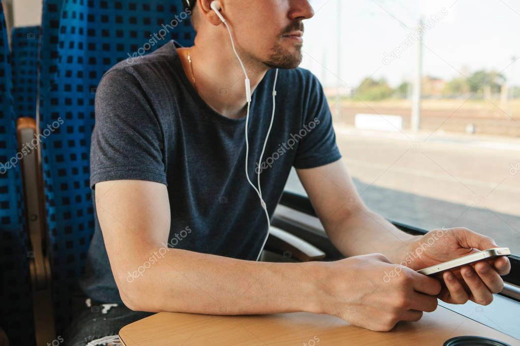 A young man listens to a music or podcast while traveling in a train