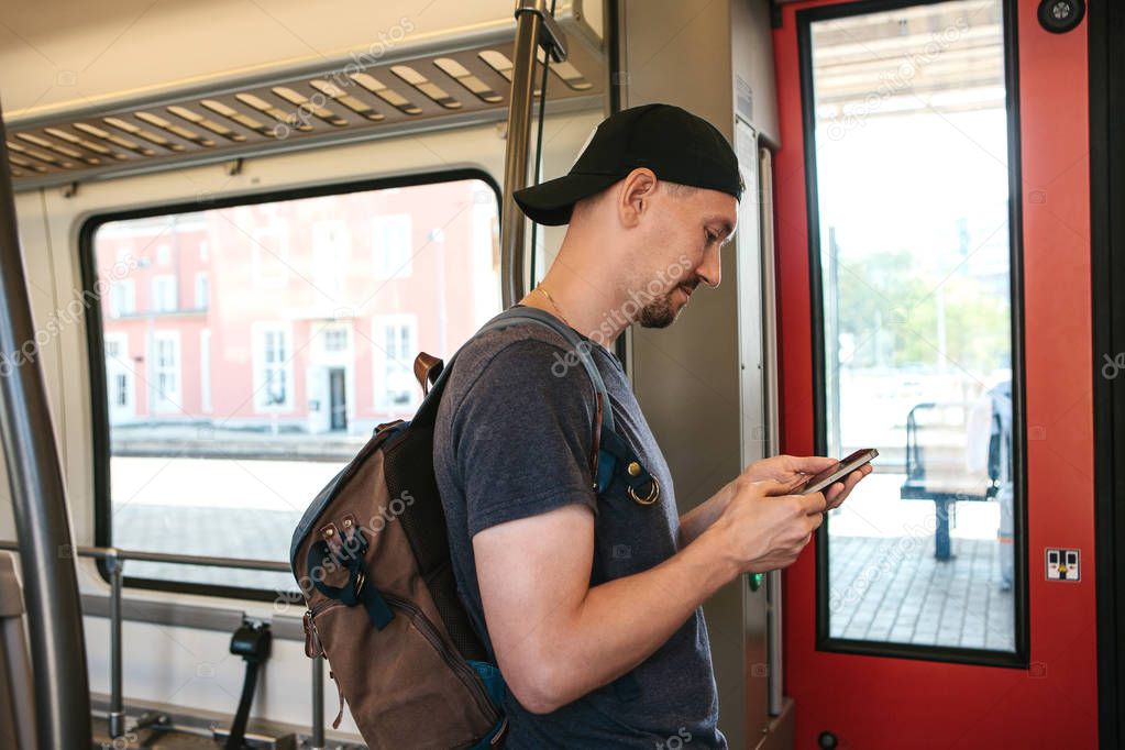 A tourist on the train uses a mobile phone.