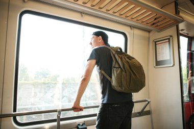 Bir sırt çantası içinde tren ile genç bir adam pencereden baktığında.