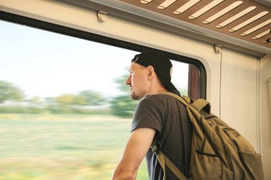 Bir sırt çantası içinde tren ile genç bir adam pencereden baktığında.