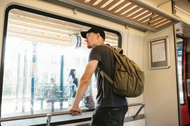 Bir sırt çantası içinde tren ile genç bir adam pencereden baktığında.
