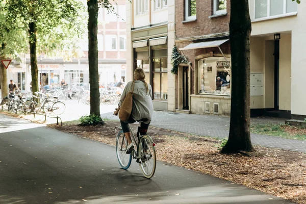 Kobietą jeżdżę rowerem wzdłuż ścieżki rowerowej. Życie codzienne miasta. — Zdjęcie stockowe
