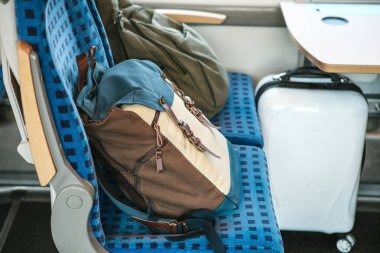 Two backpacks on the seats in the train clipart