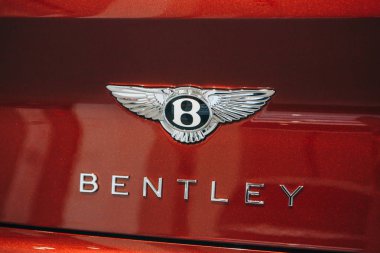 Kırmızı araba arkasında bir Bentley amblemi, yakın çekim.