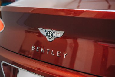 Kırmızı araba arkasında bir Bentley amblemi, yakın çekim.
