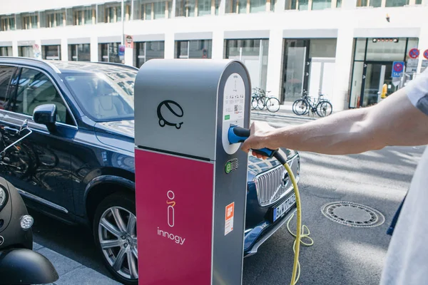 Street electric filling station for electric car refueling. Eco-friendly mode of transport. A person inserts a cord or cable to charge a car. — Stock Photo, Image