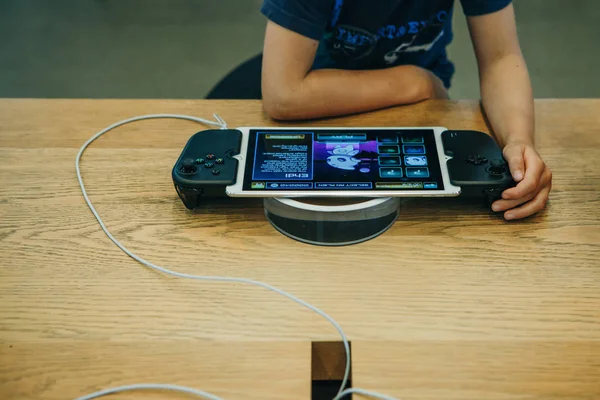 Un bambino gioca a un gioco elettronico su una console di gioco Apple o su un iPad con uno speciale joystick che si trasforma in una console . — Foto Stock