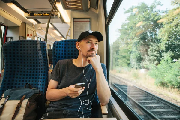 Egy fiatal ember hallgat zenét vagy podcast egy vonaton utazás közben — Stock Fotó